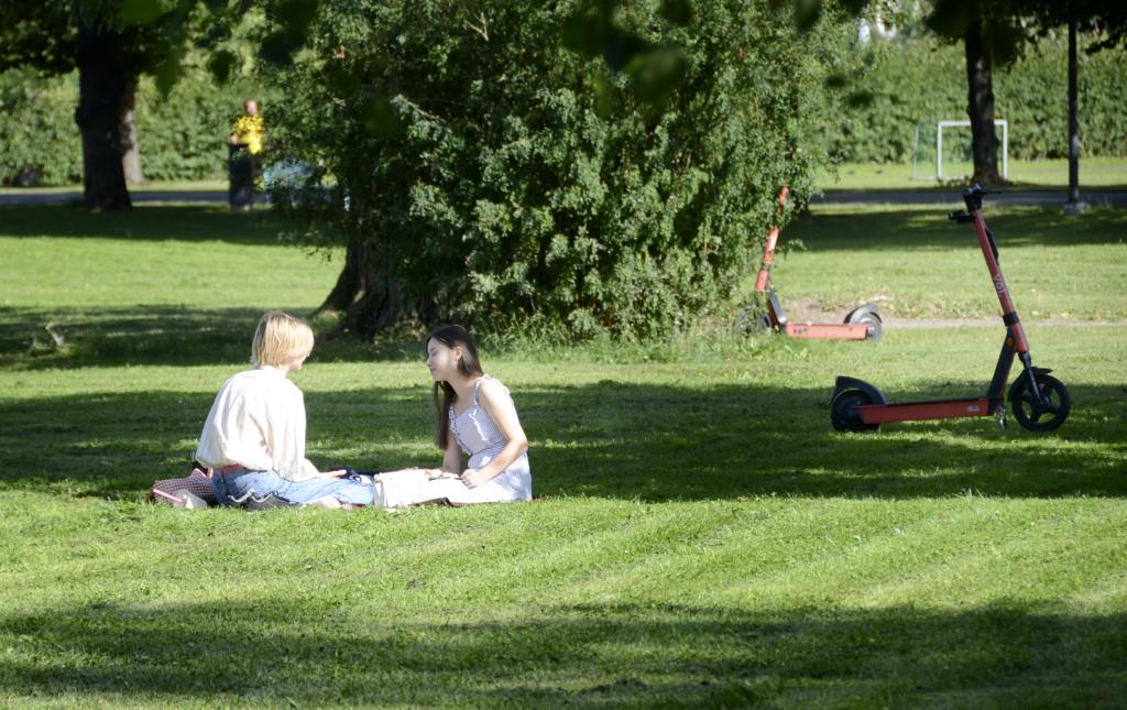 Nuori kaksikko istuskelemassa Kupittaanpuistossa kesällä.